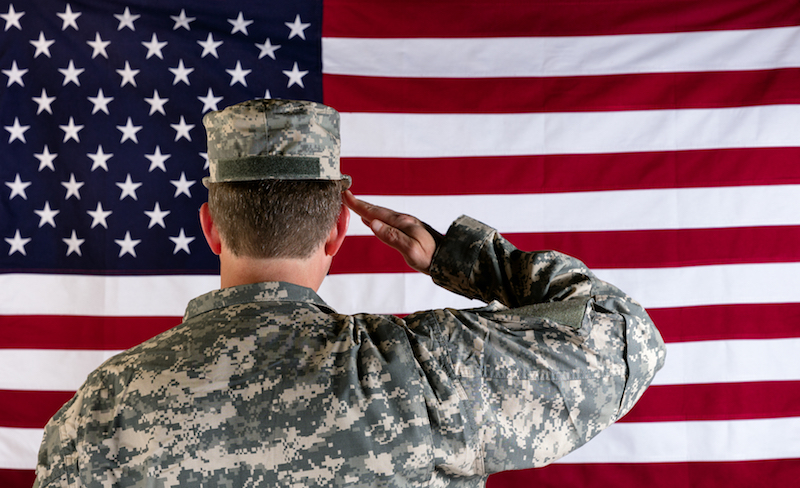 Veteran soldier back to camera saluting United States of America flag.