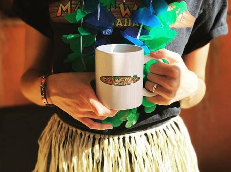 Lady wearing a Hawaiian outfit drinking Maui Wowi coffee